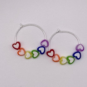 May include: Rainbow heart hoop earrings with silver hoops and white heart centers.