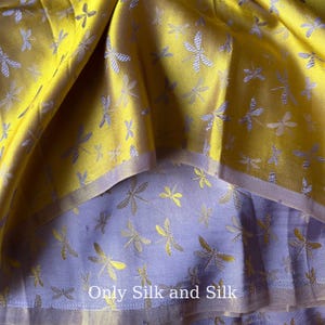 Könnte beinhalten: Nahaufnahme eines gefalteten Stoffes mit einer gelben Oberschicht und einer lavendelfarbenen Unterschicht. Beide Schichten sind mit einem Libellenmuster verziert. Der Text "Only Silk and Silk" ist unten sichtbar.