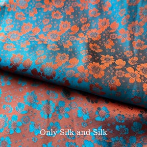 Peut inclure: Gros plan sur un tissu à motifs floraux. Le tissu a un fond turquoise avec des fleurs orange. Les fleurs ont des centres turquoise. Le texte "Only Silk and Silk" est visible sur le tissu.