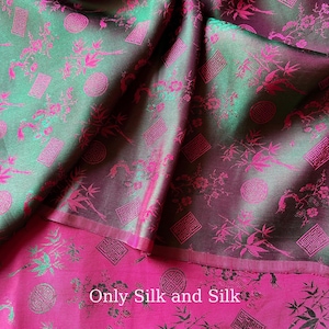 May include: Close-up of a silk fabric with a floral pattern. The fabric has a two-tone effect, with a green and purple background and a bright pink floral design. The text "Only Silk and Silk" is visible at the bottom.