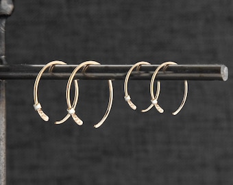 May include: Three gold hoop earrings with a small diamond accent on each hoop.