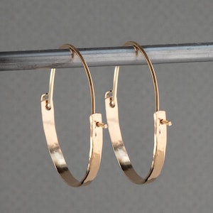 May include: A pair of gold hoop earrings with a hammered finish. The hoops are about 1 inch in diameter.