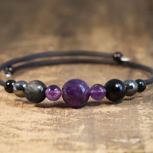 May include: A black elastic bracelet with amethyst and black onyx beads. The bracelet has a silver clasp.