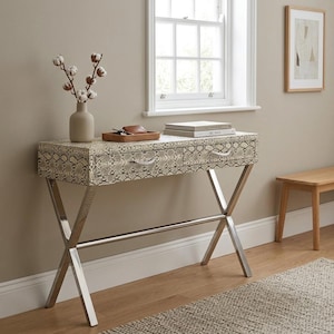 May include: A console table featuring a snakeskin design on the drawers and top, supported by a polished chrome frame. The table has two drawers with decorative handles. A vase with cotton stems, books, and a small tray are on top.