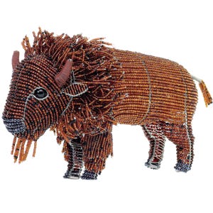 May include: A brown beaded bison sculpture with a wire frame. The bison has a long mane and a long tail. The beads are all the same size and are a dark brown color.