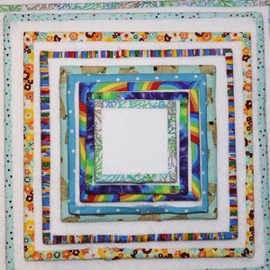 May include: A square quilt with multiple layers of fabric, each with a different colorful pattern. The layers are arranged in a concentric square pattern, creating a visually appealing design.