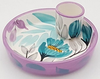 May include: A white ceramic dish with a purple rim and floral design. The dish has a small, separate cup with a purple rim and floral design.