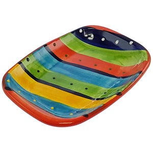May include: A colourful ceramic serving dish with a striped pattern in shades of red, yellow, green, and blue. The dish has a rectangular shape with rounded corners and a slightly raised rim.