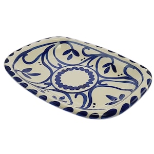 May include: A white ceramic rectangular serving dish with a blue and white floral design. The dish has a scalloped edge and a raised rim.