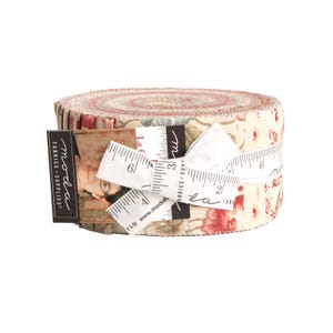 May include: A rolled bundle of fabric strips, featuring a floral pattern in red, cream, and beige. The fabric is tied with a white measuring tape and a label that reads "moda fabrics + supplies".
