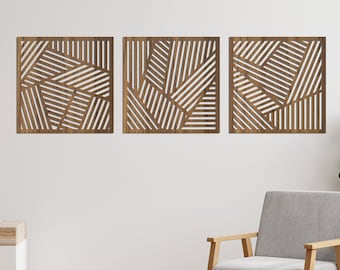 May include: Three wooden wall decor panels with a geometric pattern of intersecting lines. The panels are brown and have a natural wood finish. The panels are hanging on a white wall in a living room setting.