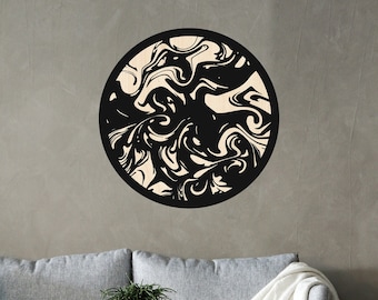 May include: A black and white abstract swirl design wall decor in a circular wooden frame. The decor is hanging on a gray wall above a gray couch and a wooden side table with a book and two bowls on top.
