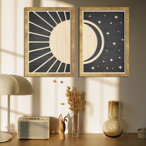 May include: Two framed wood wall art prints with a black background. The left print features a sun with rays and the right print features a crescent moon with stars.