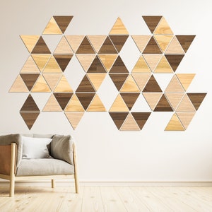 Può includere: Una poltrona color marrone chiaro con un cuscino bianco si trova di fronte a una parete bianca con un motivo geometrico di triangoli di legno marrone chiaro e scuro.