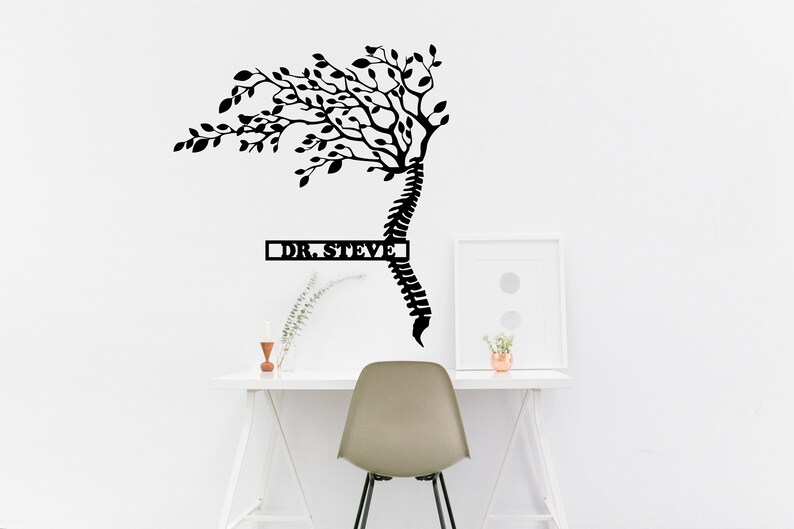 May include: Black metal wall art featuring a stylized tree with branches growing from a human spine. The tree is labeled "DR. STEVE" in a rectangular box.