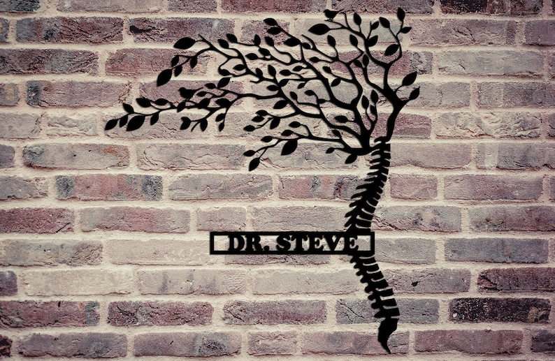 May include: Black metal wall art featuring a stylized tree with branches growing from a human spine. The art piece has a rectangular nameplate with the text "DR. STEVE" on a brick wall background.