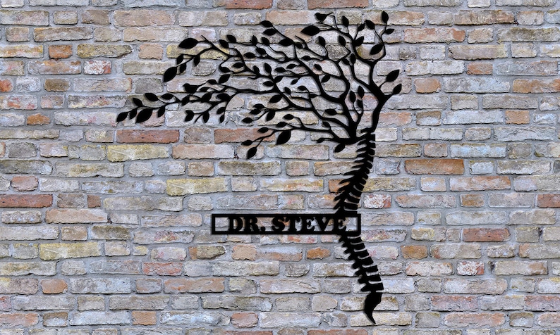 May include: Black metal wall art featuring a stylized tree with branches growing from a human spine. The tree is silhouetted against a brick wall. The text "DR. STEVE" is displayed on a rectangular plaque below the tree.