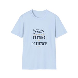 Puede incluir: Camiseta azul claro con el texto "Faith + Testing = Patience" en una fuente decorativa. El diseño incluye detalles florales y de hojas. La camiseta es de cuello redondo y manga corta.