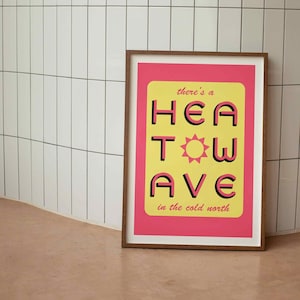 'Heatwave in the Cold North' print. Pink/yellow with the words 'there's a' & 'in the cold north' at the top/bottom, and 'HEATWAVE' over in pink in the middle with a sunshine. Against tiled wall. Colour Combo 4