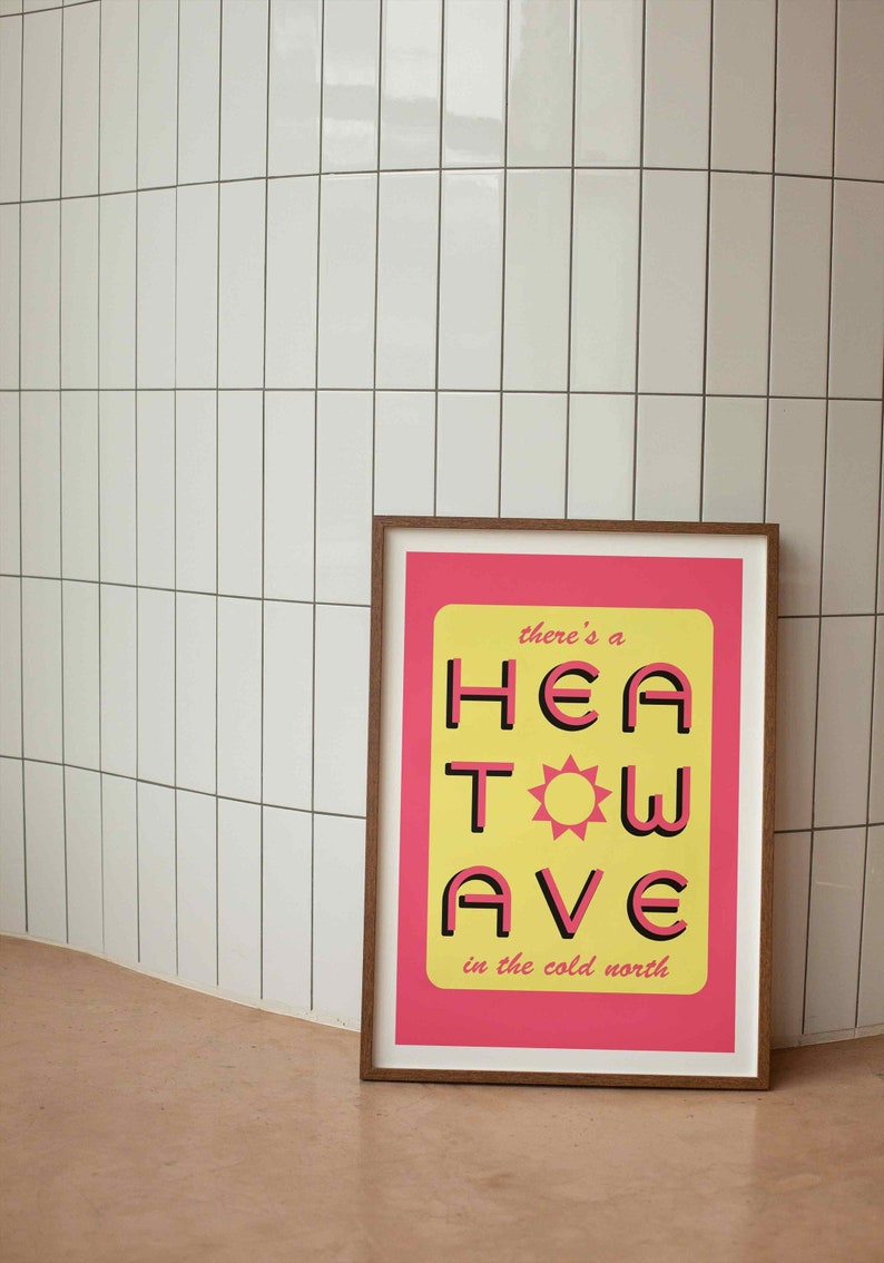 'Heatwave in the Cold North' print. Pink/yellow with the words 'there's a' & 'in the cold north' at the top/bottom, and 'HEATWAVE' over in pink in the middle with a sunshine. Against tiled wall. Colour Combo 4