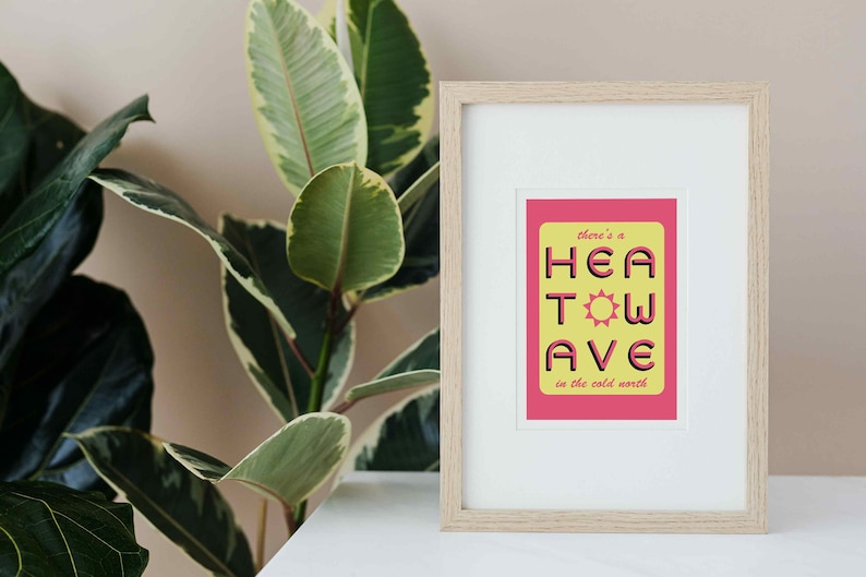 'Heatwave in the Cold North' print. Pink/yellow with the words 'there's a' and 'in the cold north' at the top/bottom, & 'HEATWAVE' in pink in the middle with a sunshine. On white background. Colour Combo 4