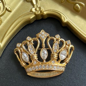 Broche vintage con corona de diamantes de imitación transparentes en tono dorado firmado por KJL para Avon