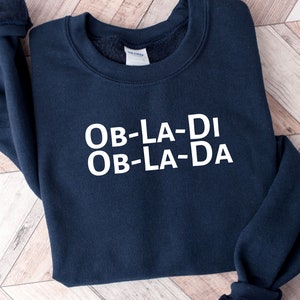 May include: A navy blue sweatshirt with the text "OB-LA-DI OB-LA-DA" printed in white on the front.