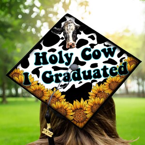 Może przedstawiać: Czapka absolwenta ozdobiona wzorem w krowie łaty, słonecznikami i tekstem "Holy Cow I Graduated".