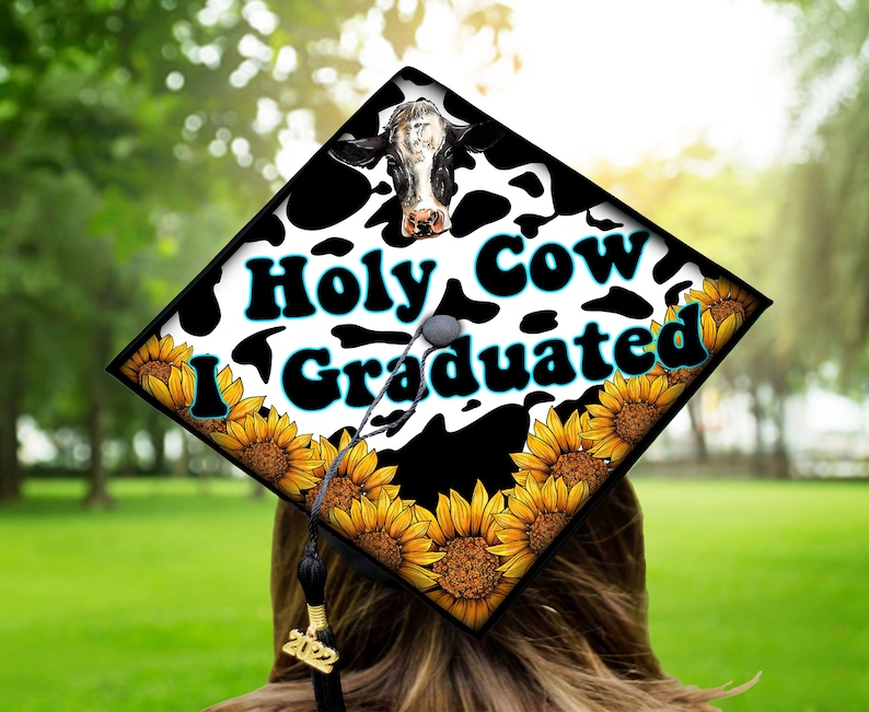 Może przedstawiać: Czapka absolwenta ozdobiona wzorem w krowie łaty, słonecznikami i tekstem "Holy Cow I Graduated".