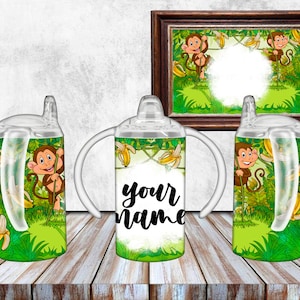 May include: Three clear plastic cups with handles and a straw. The cups have a jungle theme with monkeys, bananas, and green leaves. The middle cup has the text "your name" on it.