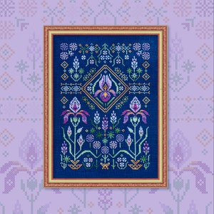 Può includere: Un ricamo a punto croce incorniciato che presenta un motivo floreale con iris viola, foglie verdi e uno sfondo blu. Il ricamo è circondato da una cornice dorata.