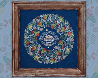Puede incluir: Un diseño de punto de cruz enmarcado que presenta una escena de invierno con una pequeña casa rodeada de una corona de ramas de pino, bayas y piñas sobre un fondo azul oscuro.