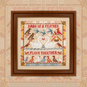 May include: A framed cross-stitch sampler with a white background and colorful embroidery. The sampler features a variety of birds, including swans, robins, and cardinals. The text "Birds of a Feather Flock Together" is embroidered in the center of the sampler.