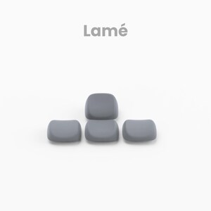 May include: Five gray keycaps arranged in a pyramid shape. The word "Lamé" is written in gray text above the keycaps.