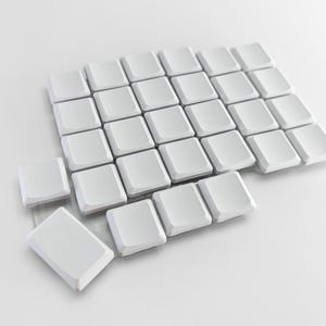 May include: A collection of white square keycaps, some arranged in a grid, others scattered. The keycaps are made of a smooth, matte material, and are set against a plain white background. The image is well-lit.