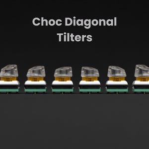 May include: A row of eight clear plastic keyboard keycaps with a yellow base and a green bottom. The keycaps are labeled "Choc Diagonal Tilters".