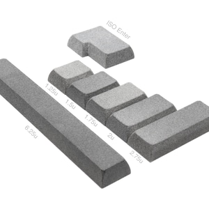 May include: A set of grey textured mechanical keyboard keycaps including a 6.25u spacebar, an ISO Enter key, and various modifier keys labeled with sizes 1.25u, 1.5u, 1.75u, 2u, and 2.75u. The keycaps have a uniform matte finish and angular edges.