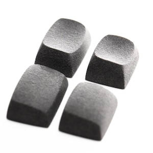 May include: Four individual dark gray keyboard keycaps with a textured, matte finish. Each keycap features a slightly concave top surface and a square base, arranged in a cluster against a plain white background for clear visibility.