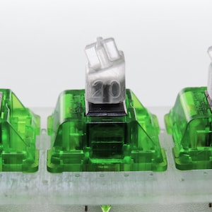 May include: Close-up of three clear, numbered keycaps (15, 20, 25) on green mechanical keyboard switches. The switches are mounted on a light-colored base. The text "Old Picture" is at the bottom.