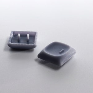 May include: Two purple plastic keyboard keys. One key has a raised, textured surface and the other key has two small holes.