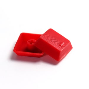 May include: Two red plastic keycaps, one with a plus sign and the other with the number one.