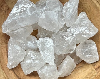 May include: A collection of clear quartz crystal chunks in various sizes and shapes. The crystals are translucent and have a natural, rough texture.