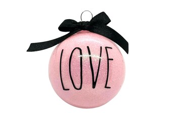 May include: Pink glitter Christmas ornament with a black bow and the word "LOVE" written in black.