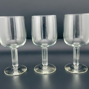 May include: Three clear glass wine glasses with a fluted stem and a round base.