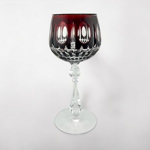 Puede incluir: Una copa de vino transparente con un borde rojo oscuro y un diseño de vidrio tallado intrincado.