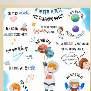 May include: A white poster with blue and orange accents features an astronaut holding balloons. The poster has several positive affirmations in German, including "Ich bin klug" (I am smart), "Ich bin sch&ouml;n" (I am beautiful), and "Ich verdiene Gutes" (I deserve good things).