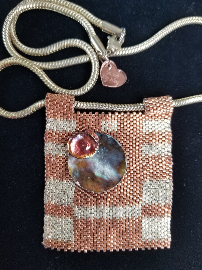 K&ouml;nnte beinhalten: Eine Halskette aus Kupfer- und Silberperlen mit einem quadratischen Anh&auml;nger, der eine runde, schillernde Muschel und eine kleinere Kupferschale zeigt. Die Halskette hat eine goldene Kette mit einem herzf&ouml;rmigen Anh&auml;nger, auf dem "Forever My Mom" steht.