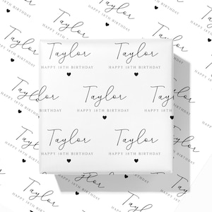 May include: White wrapping paper featuring the name "Taylor" in a repeating pattern, along with "Happy 18th Birthday" and black heart motifs. The design is in a handwritten style, suitable for a birthday present.