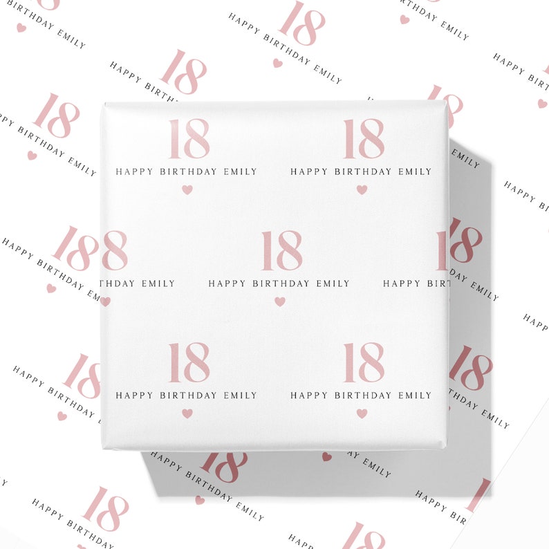 May include: White wrapping paper with a repeating pattern of the number "18", the words "Happy Birthday Emily", and small pink hearts. The design is in a soft pink color. The paper is wrapped around a gift.