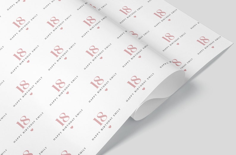 May include: White wrapping paper with a repeating pattern of the number 18 in a dusty rose color, along with the text "Happy Birthday Emily" and small hearts. The paper is partially rolled.